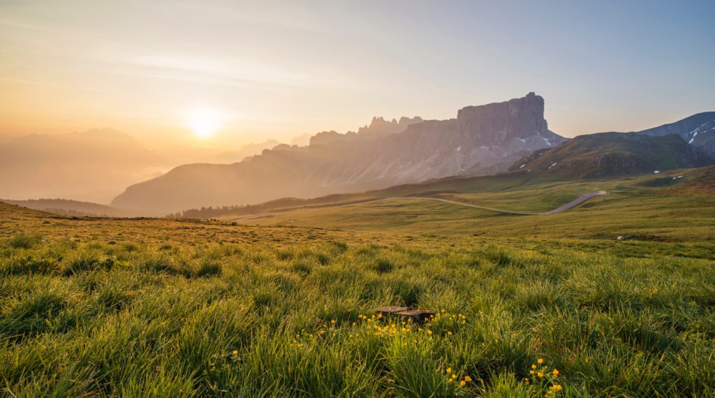 Un coucher de soleil sur des montagnes avec prairie verdoyante